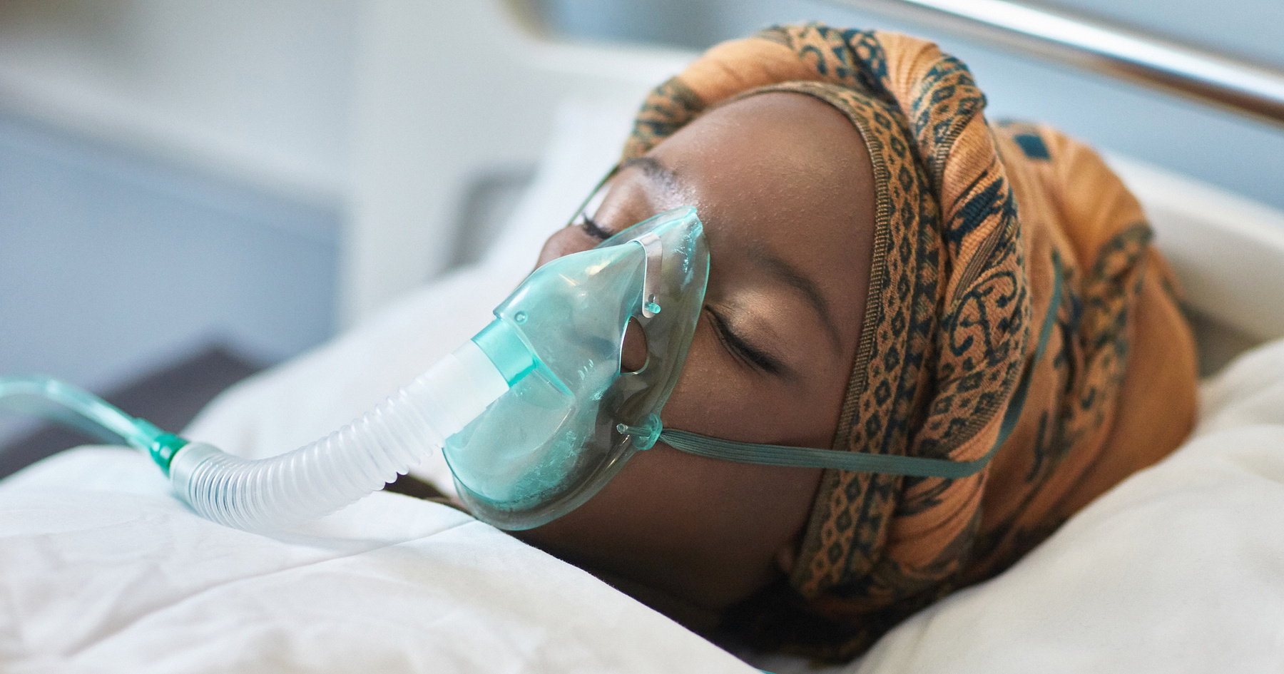 Woman in hospital bed wearing oxygen mask