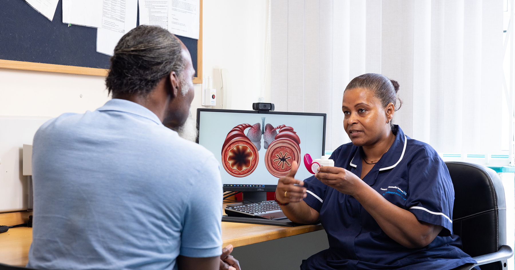 Respiratory nurse sitting with patient to demonstrate inhaler
