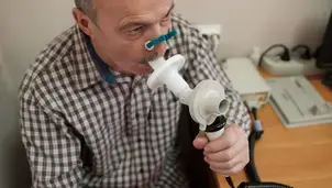 Senior man testing breathing function by spirometry 