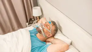 Man lying on bed wearing a ventilation mask