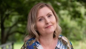 Smiling blonde woman outdoors in a colorful blouse