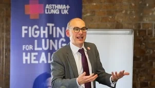 Man speaking in front of a poster that says fighting for lung health