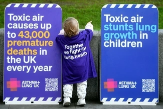 Child beside toxic air posters pointing into playground