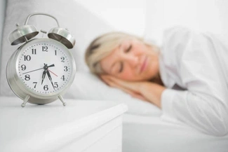 A woman sleeping next to her alarm clock