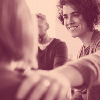 Woman smiling and touching another person's shoulder